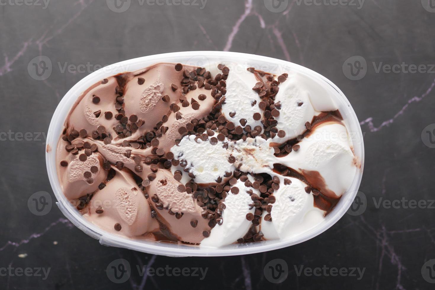 chocolate ice cream in a plastic container on black photo