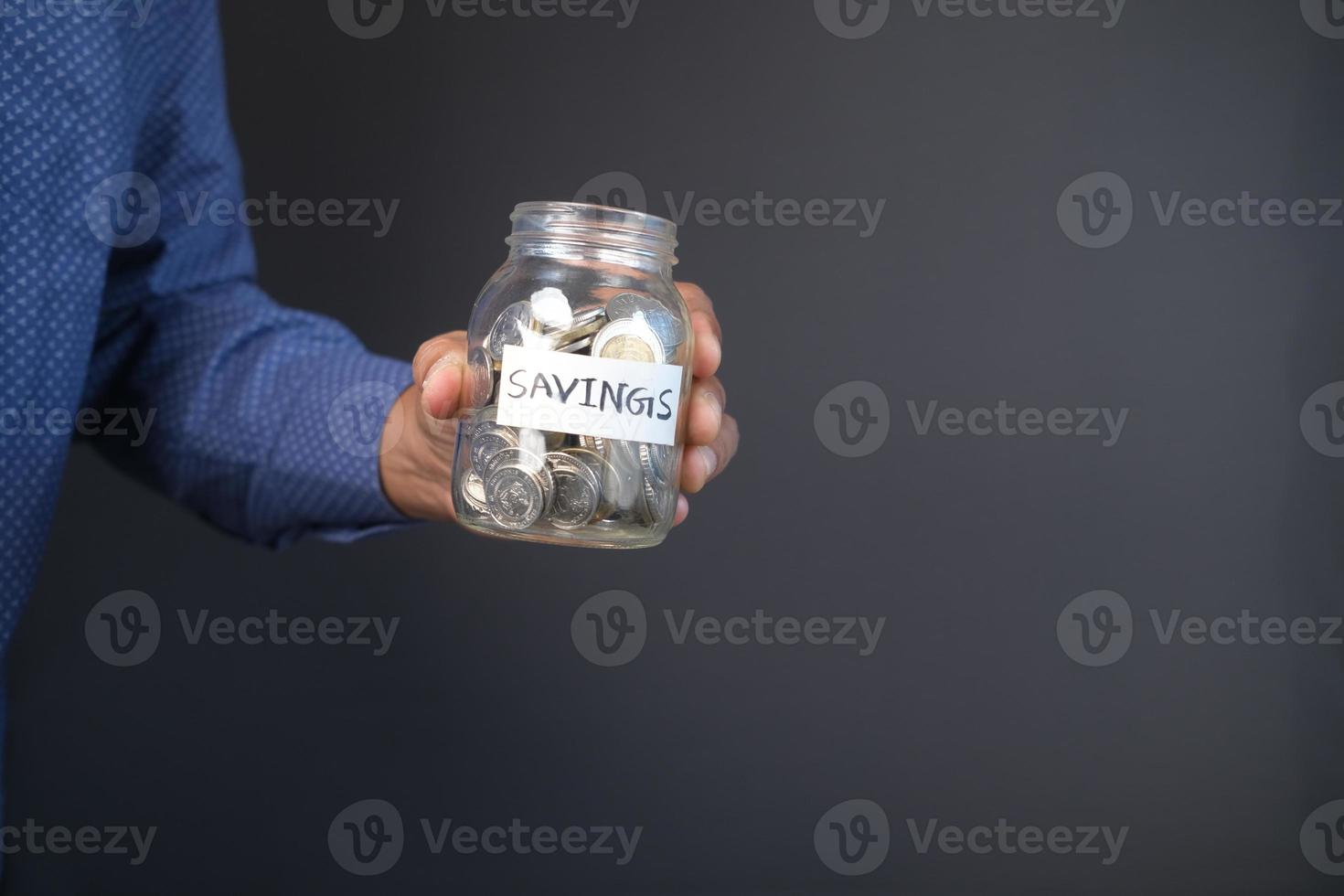 young man saving coins in a jar white sited photo