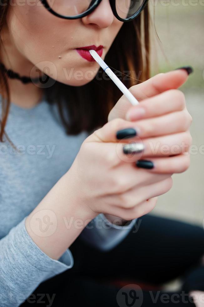 Young girl lighting cigarette outdoors close up. Concept of nicotine addiction by teenagers. photo