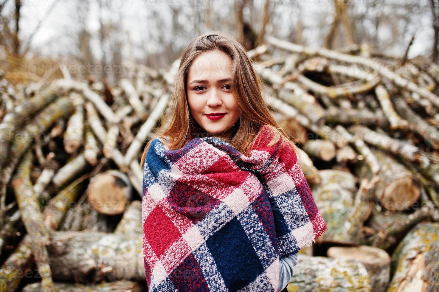 Young hipster girl wear on blanket against wooden stumps on wood. photo