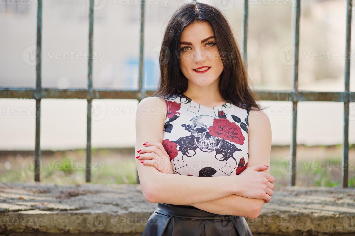 Young goth girl on black leather skirt against iron fence. photo