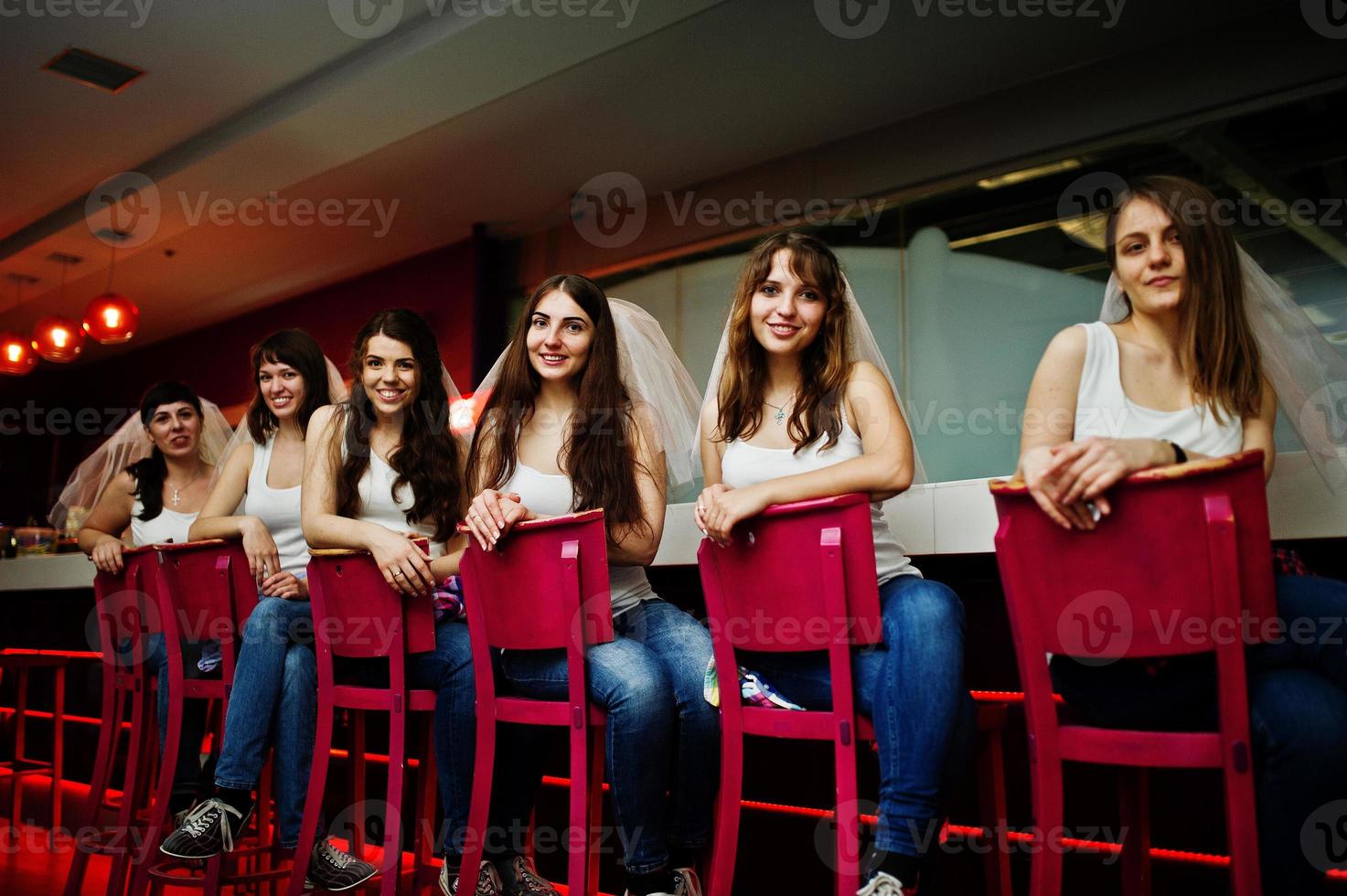 Six girls on veil sit at the bar stools on hen party. photo