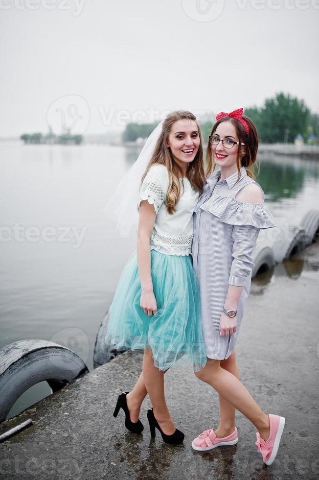 Fantastic bride with her bridesmaid on the quay beside the lake at bachelorette party. photo