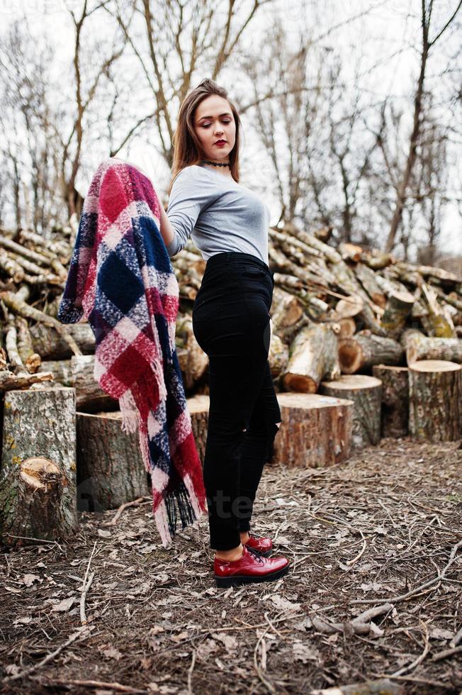 Young hipster girl wear on blanket against wooden stumps on wood. photo