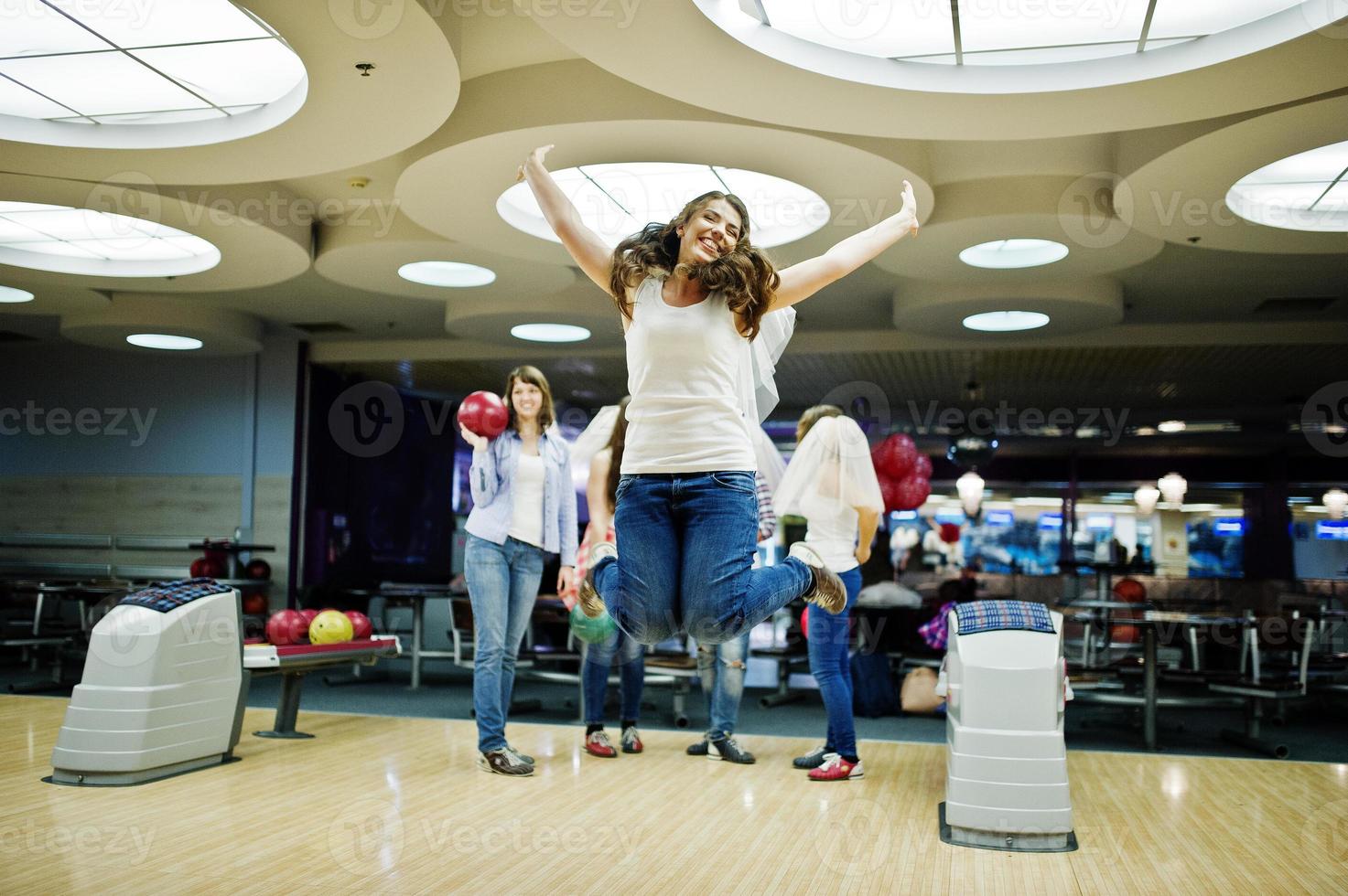 Group of girls having fun and play bowling at hen party. photo