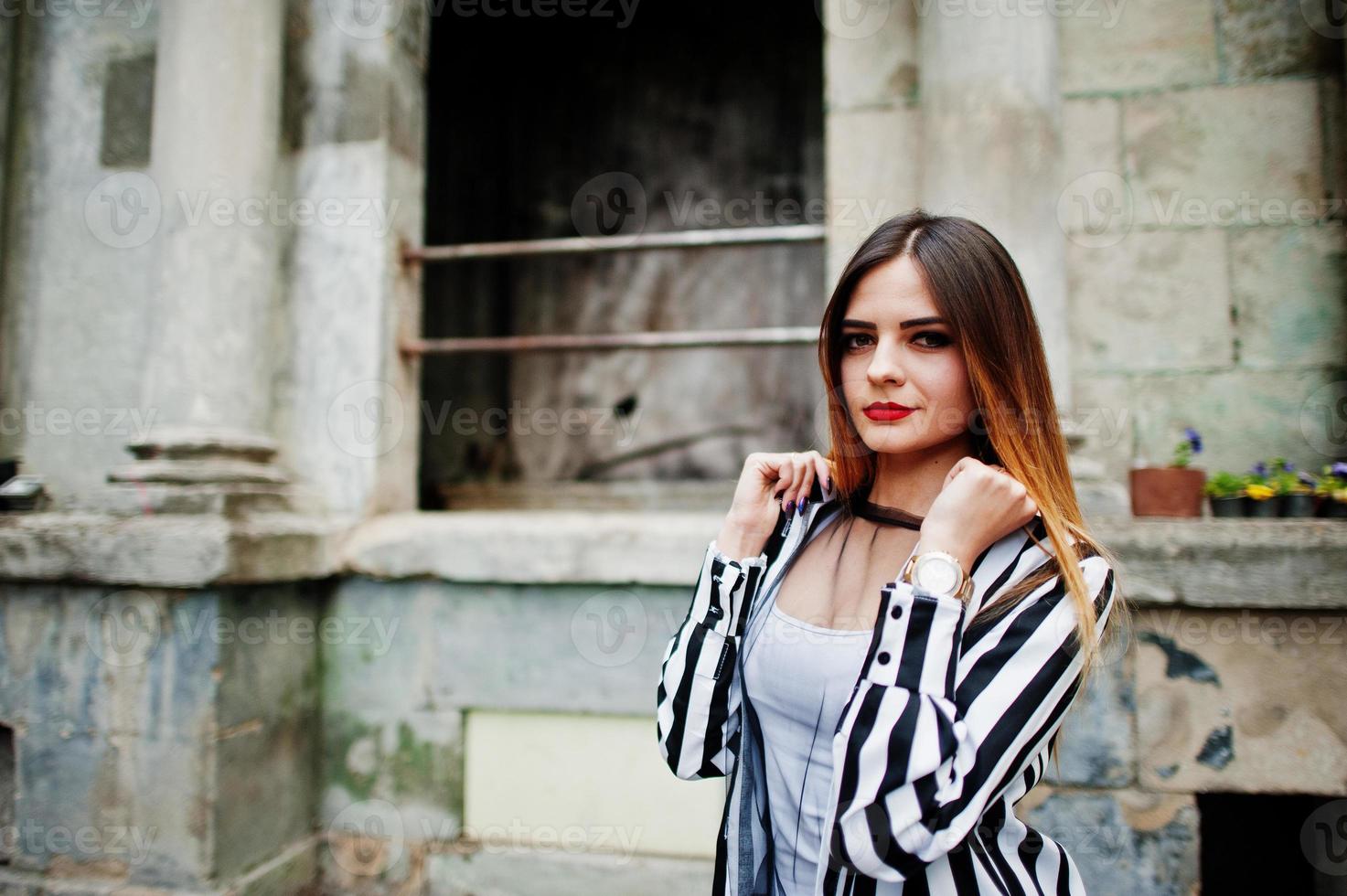 mirada de mujer de moda con chaqueta de traje a rayas blancas y negras, pantalones de cuero, posando en la calle concepto de chica de moda. 6750760 stock