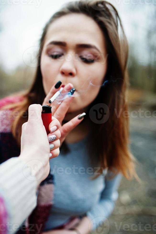 mano de niña con encendedor de cigarrillos. dejar de fumar problema social. amigos fuman. foto