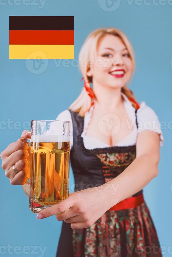 retrato de una hermosa mujer rubia alegre y sonriente vestida con un vestido nacional tradicional bávaro foto