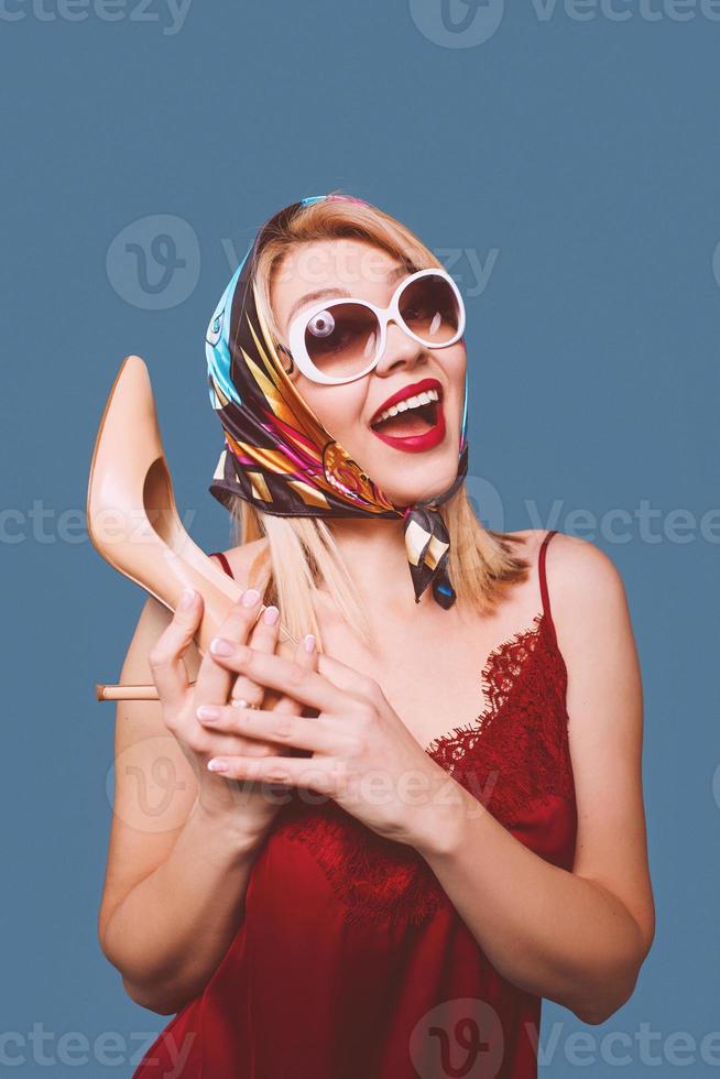 funny stylish smiling cheerful fancy blonde woman with make up and with high heel shoe in her arms and italian flag on background photo