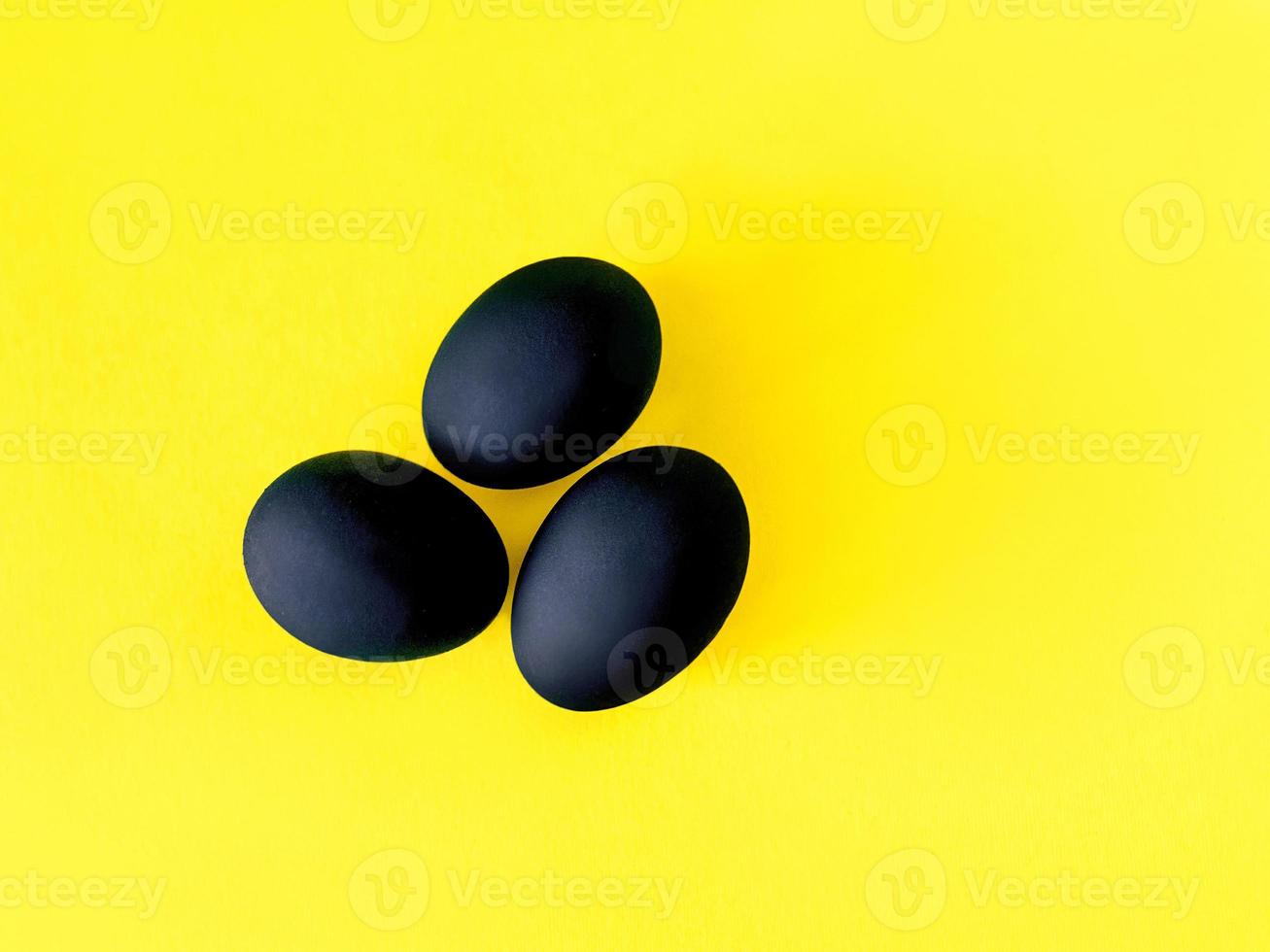 Black eggs on the yellow and violet background. Easter, diversity, geometric, pattern, food concept photo