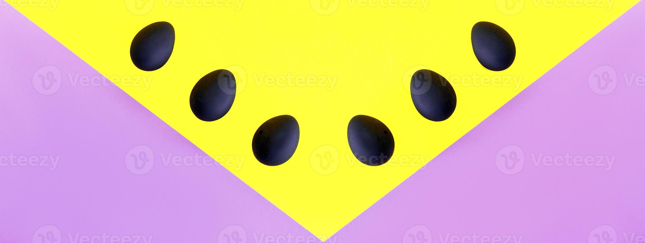 Black eggs on the yellow and violet background. Easter, diversity, geometric, pattern, food concept photo