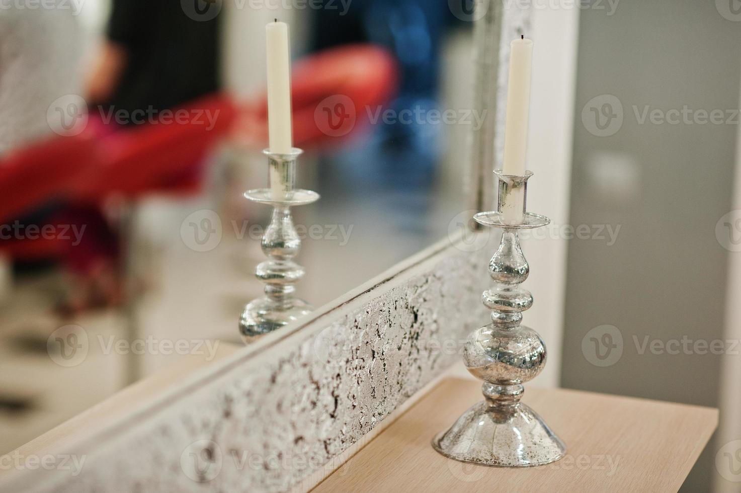 vela en candelabro de plata en el salón de belleza contra el espejo. foto