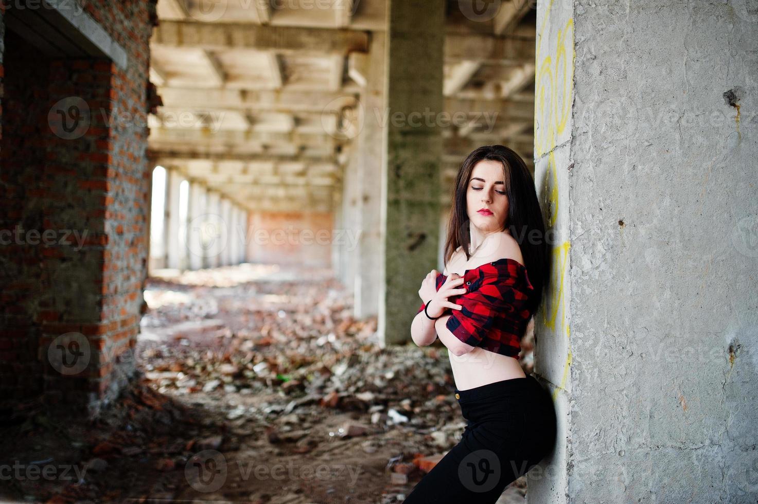 Portrait girl with red lips wearing a red checkered shirt with bare shoulders posed sexy background abadoned place. photo