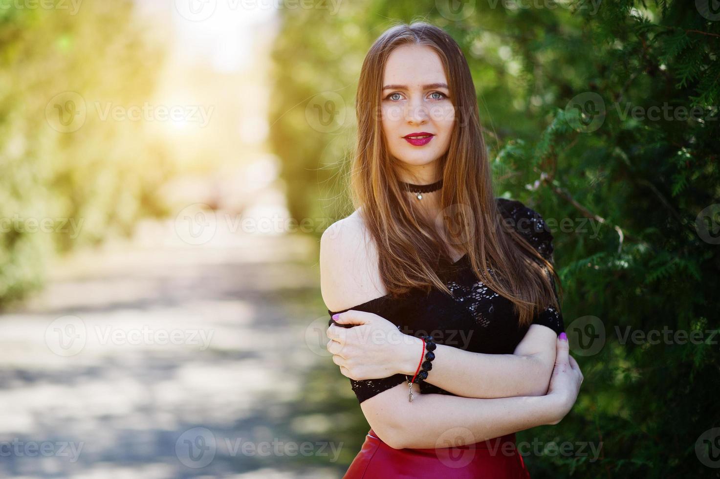 Portrait of girl with bright make up with red lips, black choker necklace on her neck and red leather skirt. photo