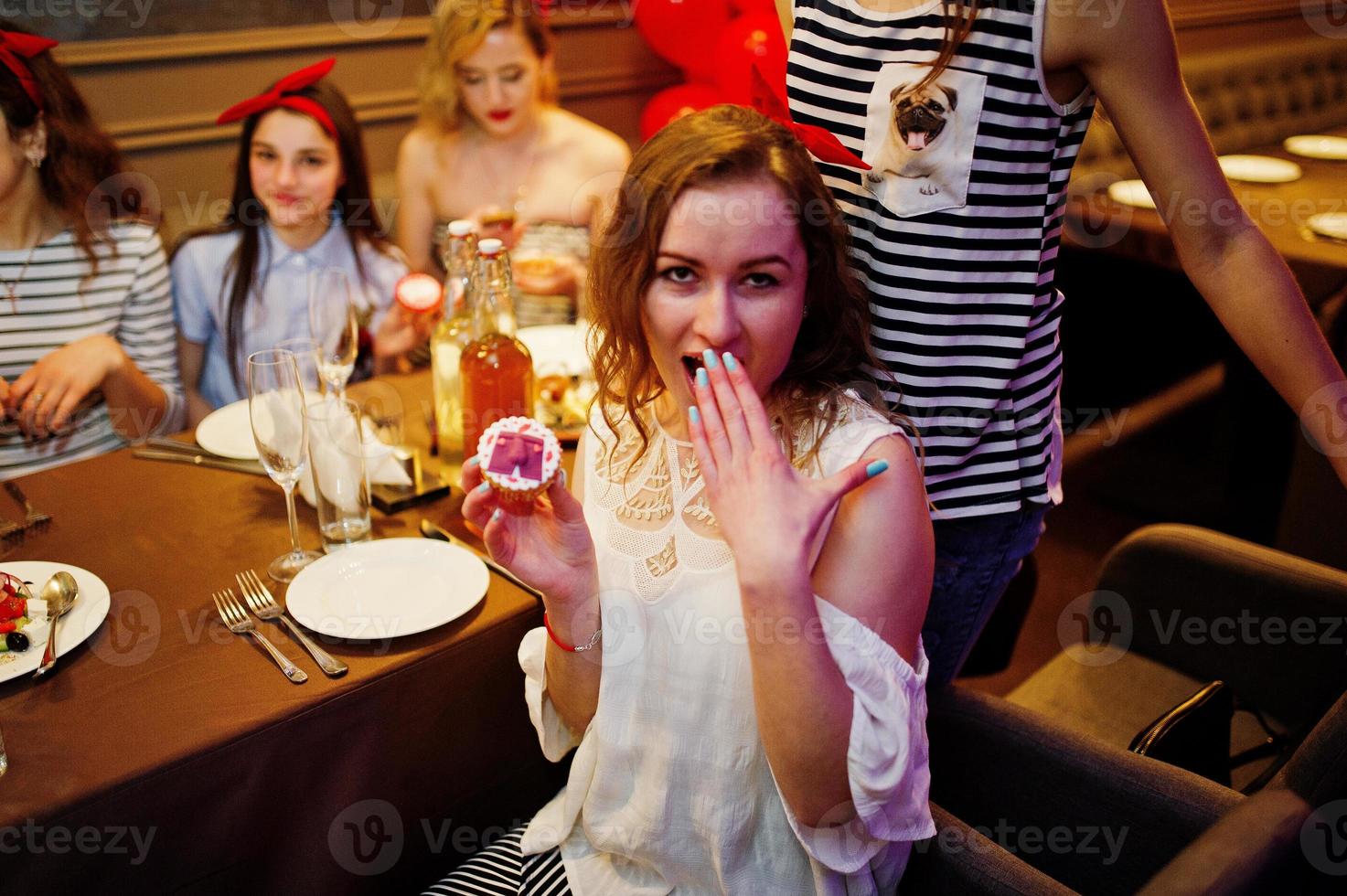 Fabulous girls posing with cupcakes in the restaurant at the bachelorette party. photo