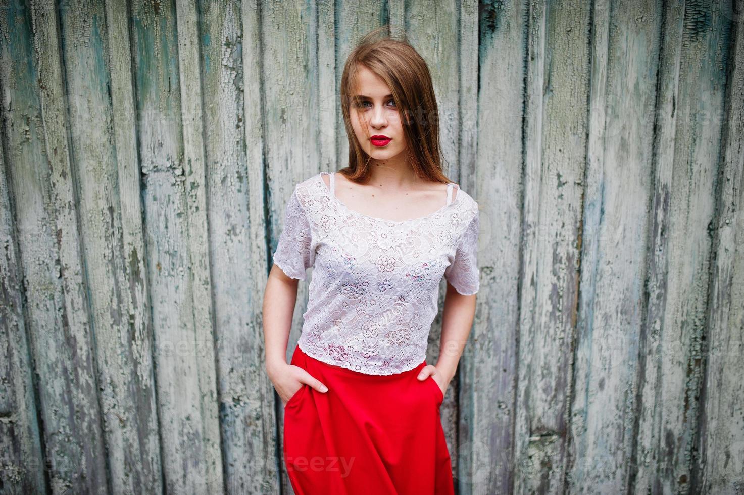 retrato de una chica hermosa con labios rojos sobre fondo de madera, vestido rojo y blusa blanca. foto