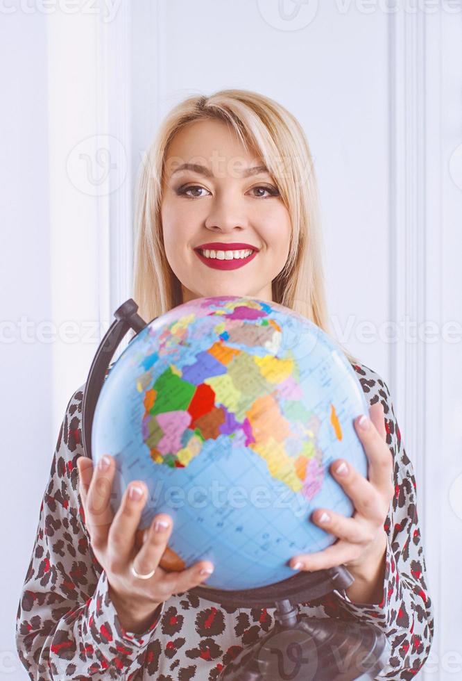 beautiful cheerful smiling blonde woman travel agent holding globe in her hands photo