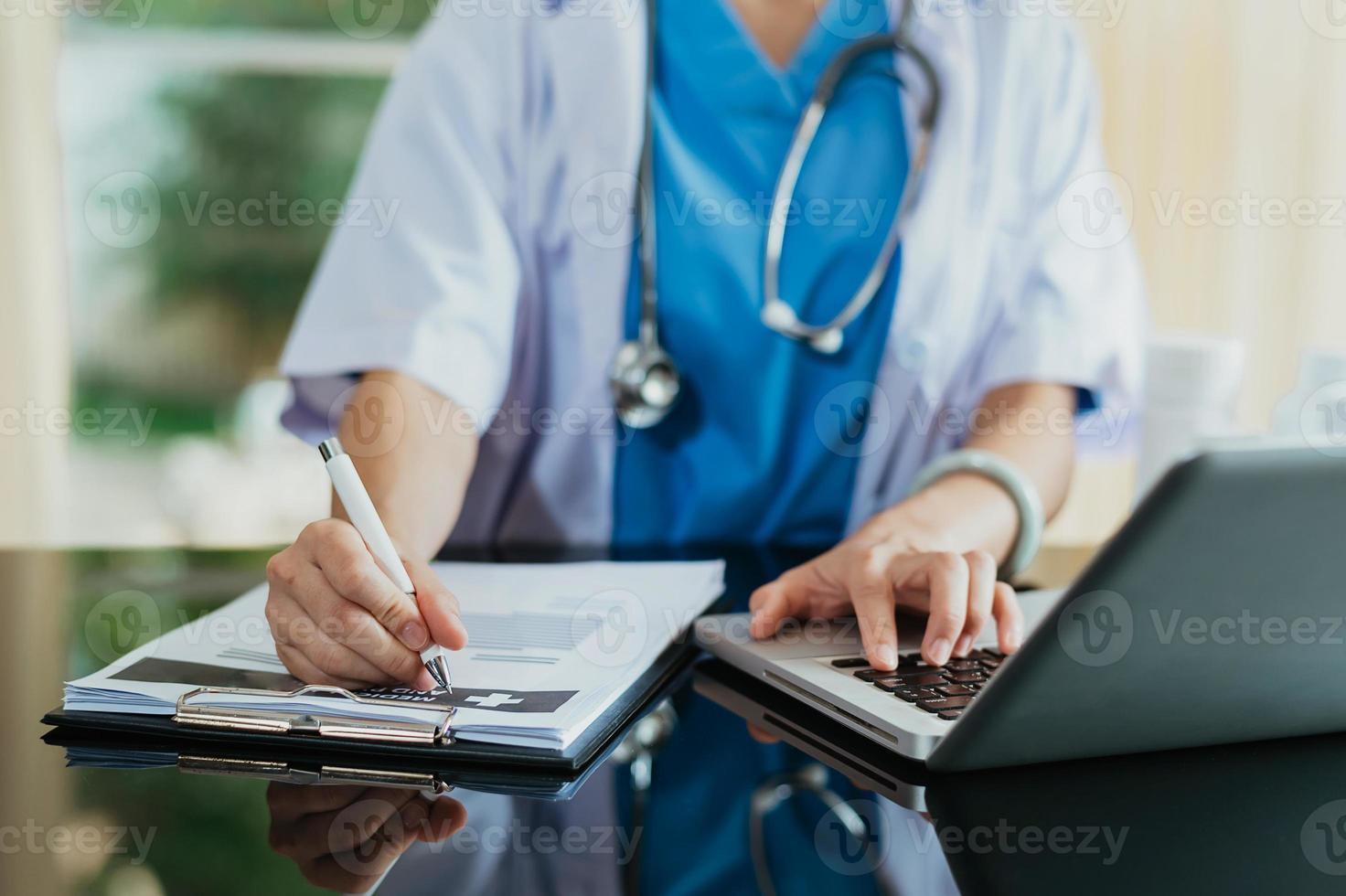 Medical technology concept. Doctor working with mobile phone and stethoscope and digital tablet laptop in modern office at hospital in morning light photo