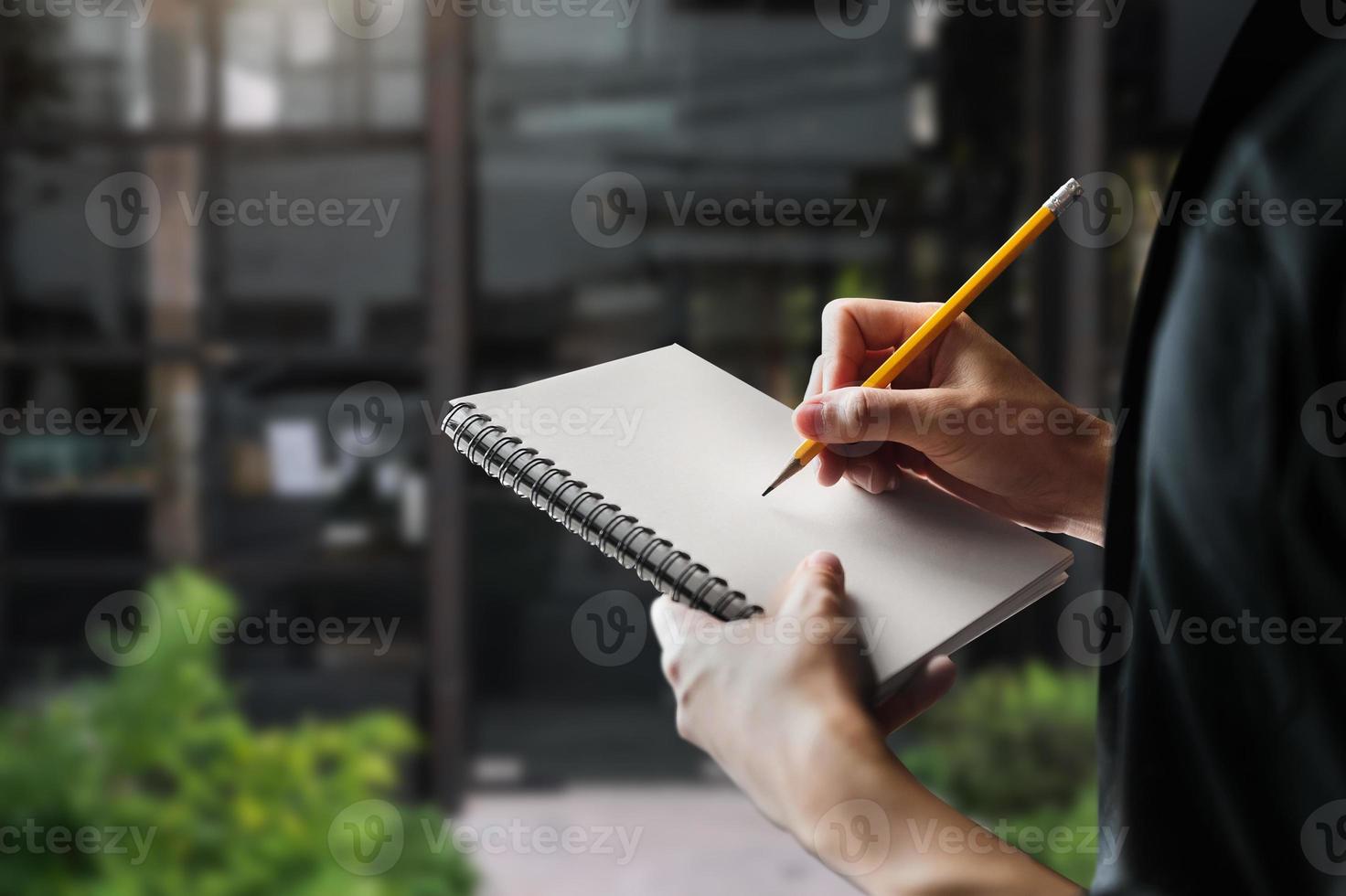 lose up of woman's hand writingis taking notes while standing over photo