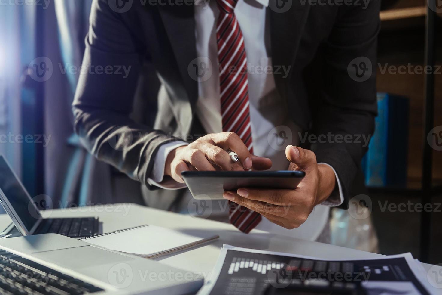 business documents on office table with smart phone and digital tablet and graph financial and man working photo