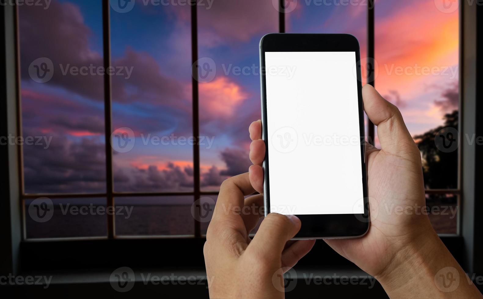 una mano de hombre sosteniendo un dispositivo de teléfono inteligente en el fondo de la vista frontal del cielo, el río y la montaña foto