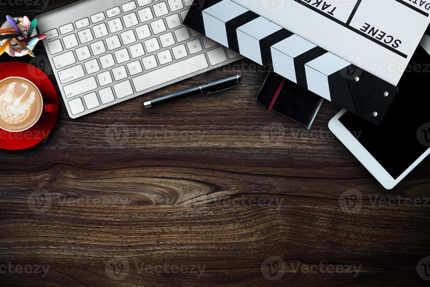 office stuff with Movie clapper, laptop, smartphone, tablet, coffee cup, pen, notepad and documents on the wood table top view shot. photo