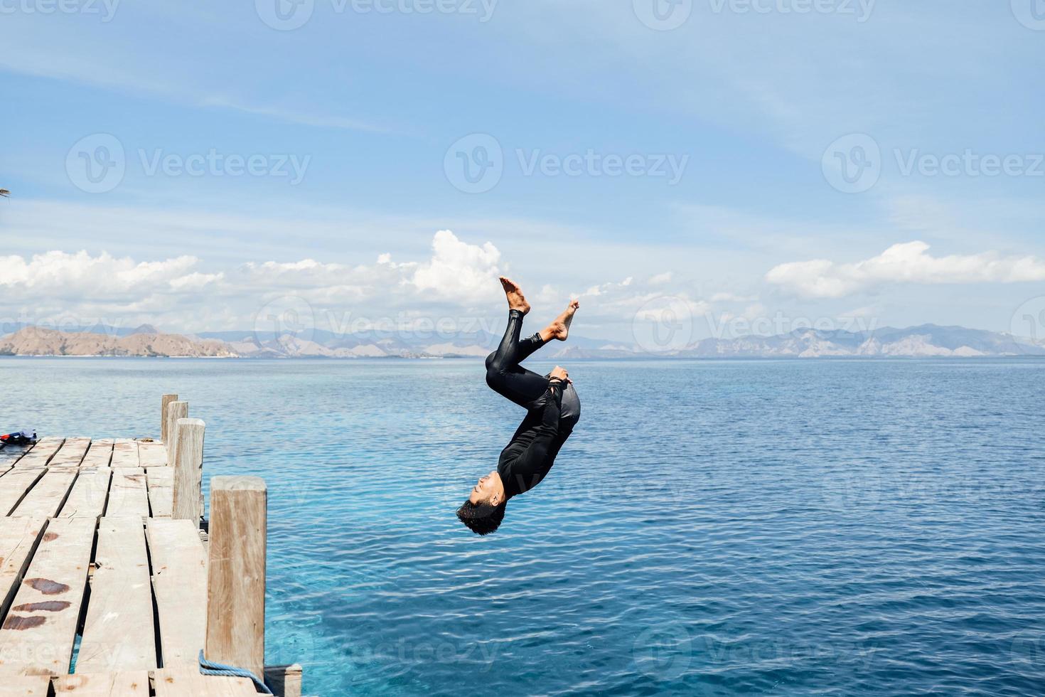 A man does a backflip into the water photo