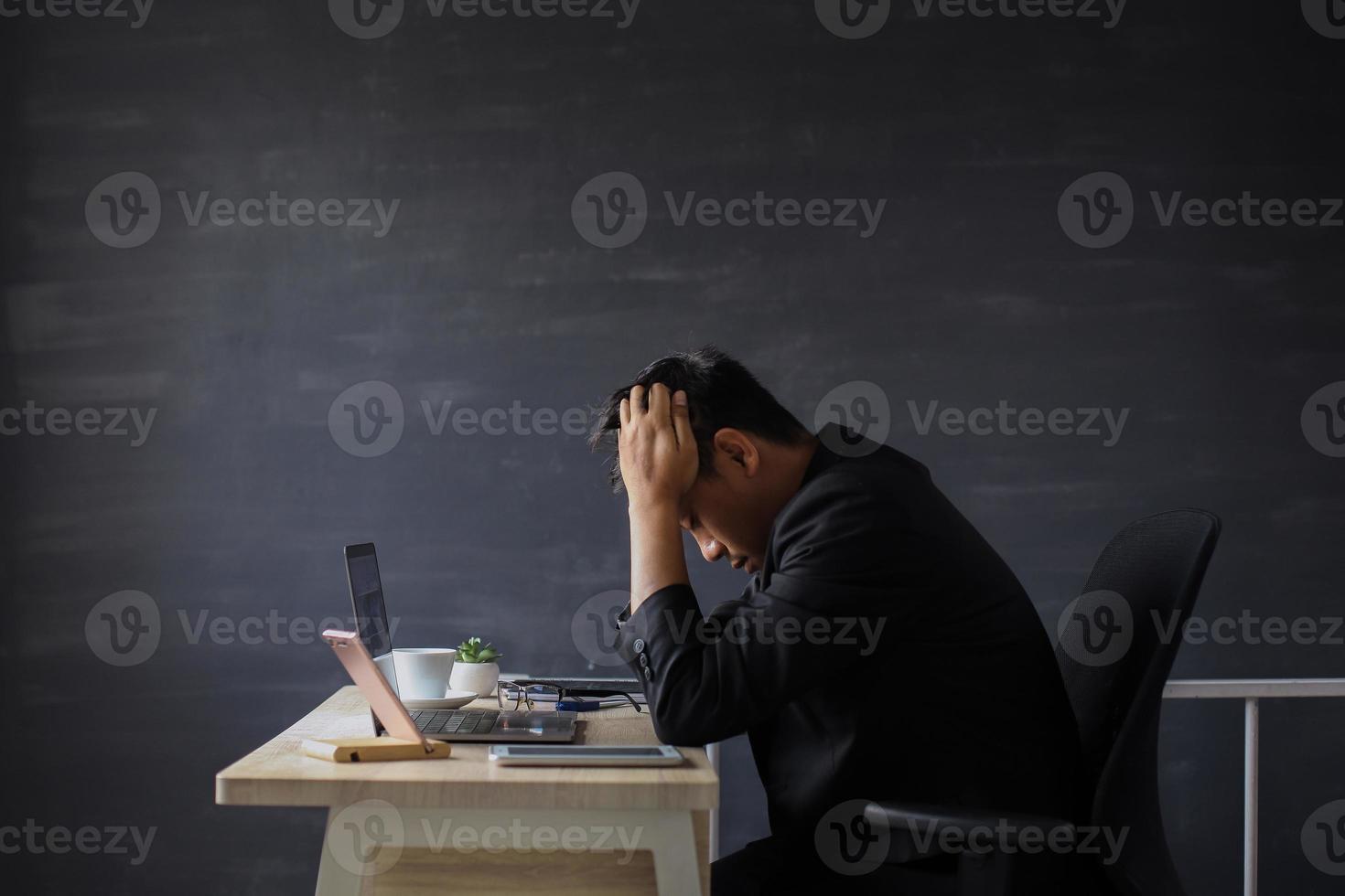 Stressed businessman pulling his hair out while sitting on his working place in office photo