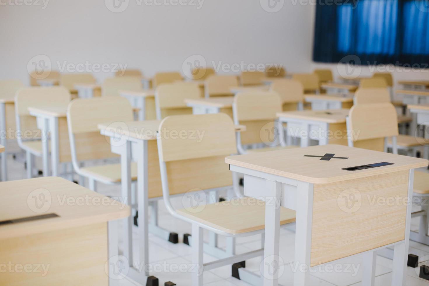 Many wooden tables and chairs well arranged in empty classroom photo