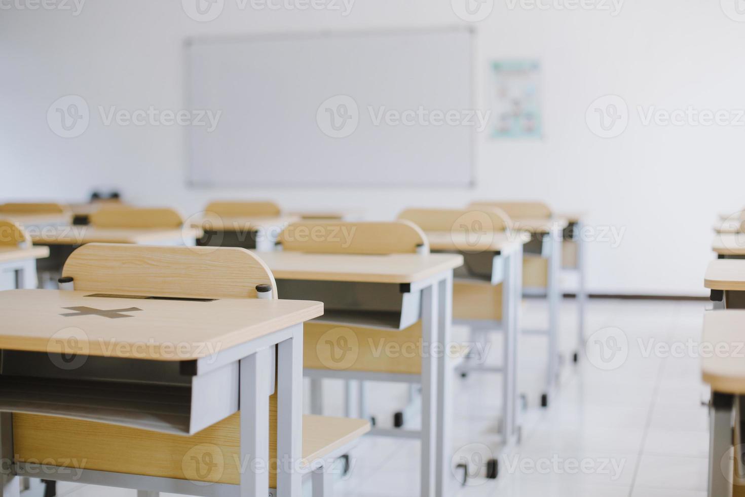 aula vacía sin estudiantes con escritorios, sillas y pizarra blanca durante la pandemia foto