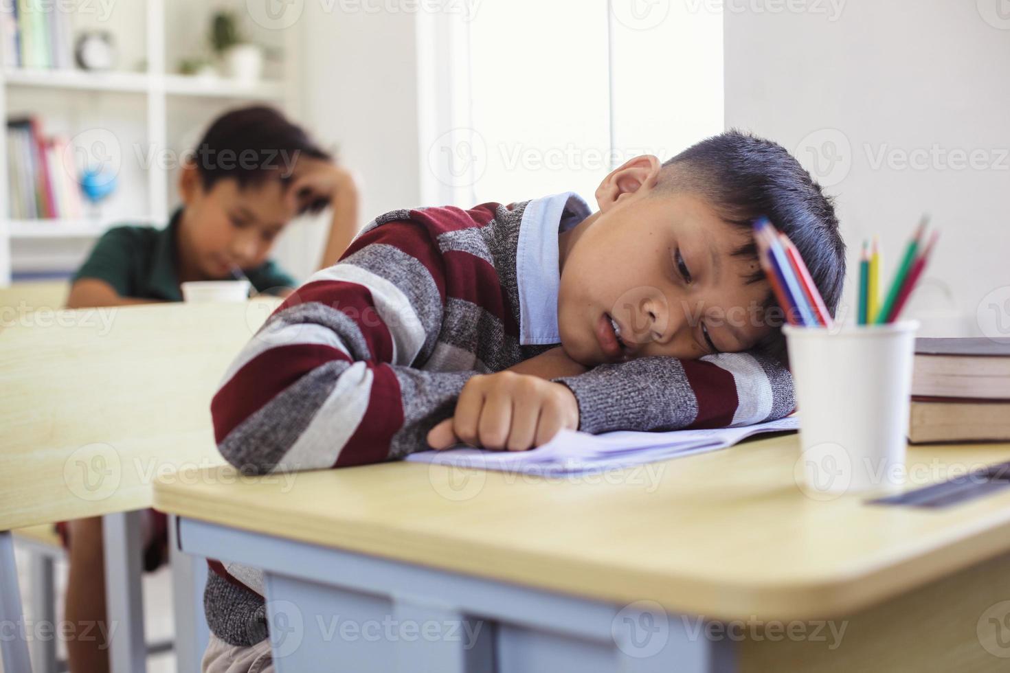 estudiante asiático cansado y somnoliento durante la lección de clase foto