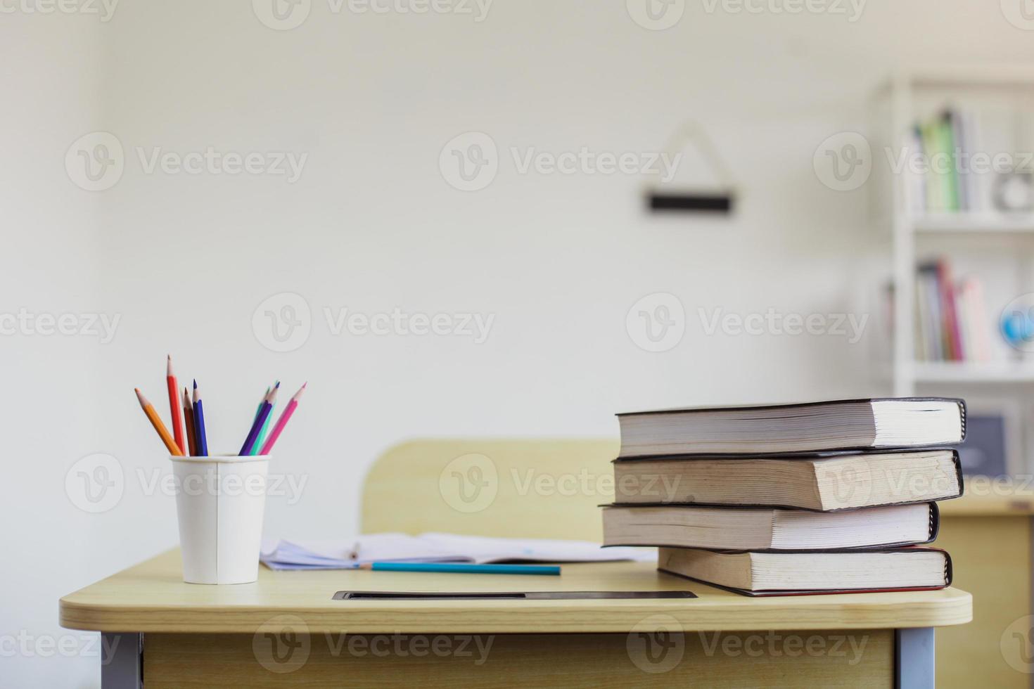 pupitre escolar vacío con papelería y pila de libros foto