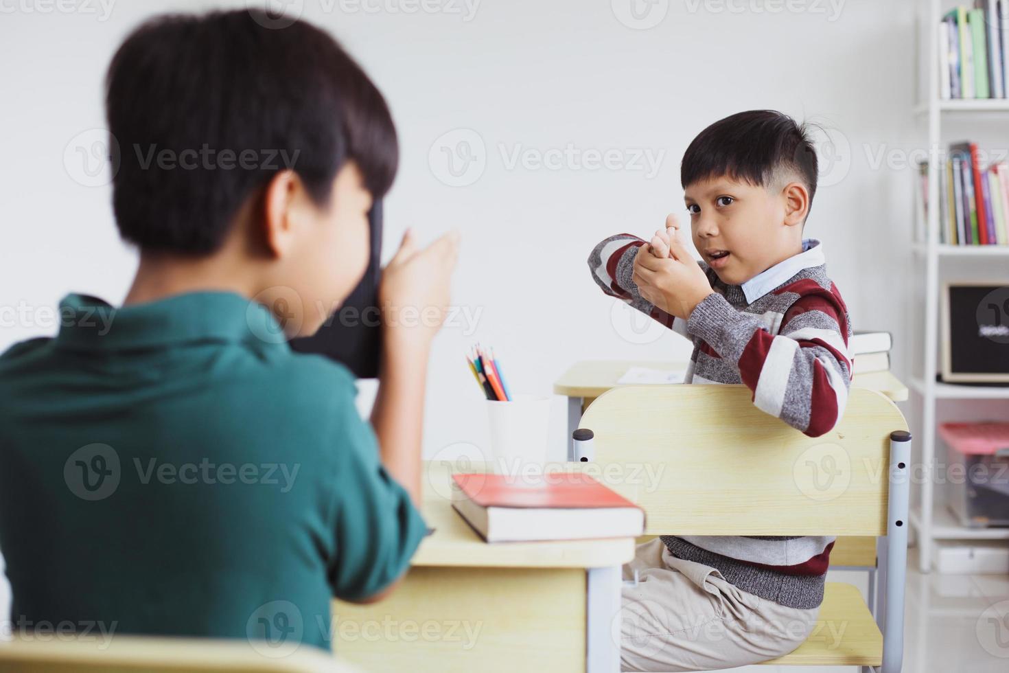 Two students having fun and playing gunfight in class photo