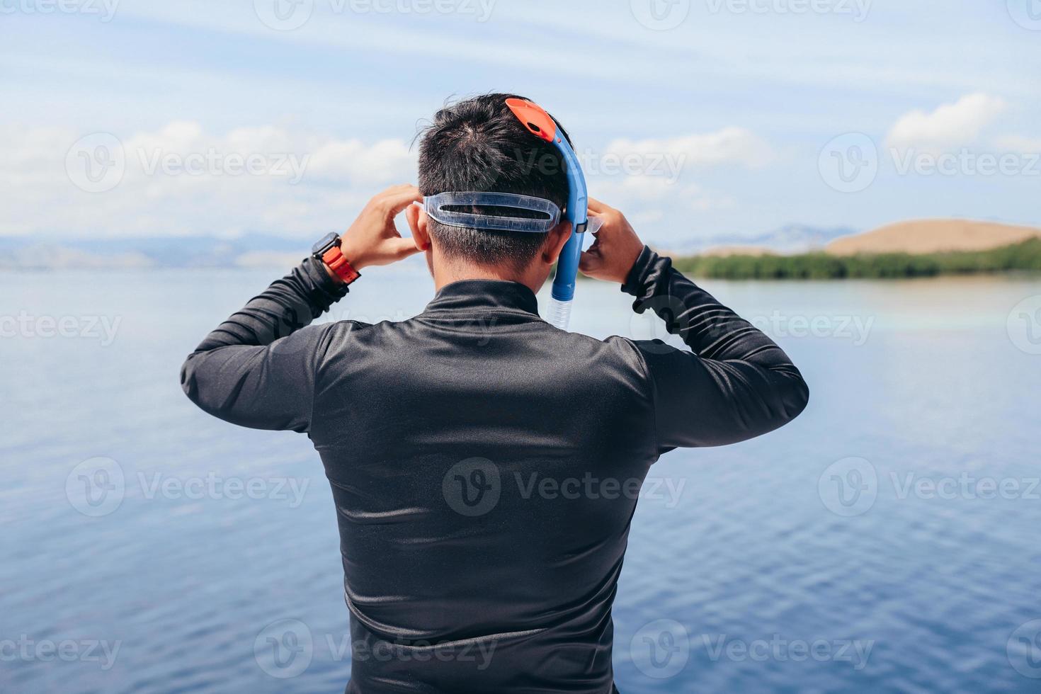 hombre en traje de neopreno preparándose para bucear en el mar foto