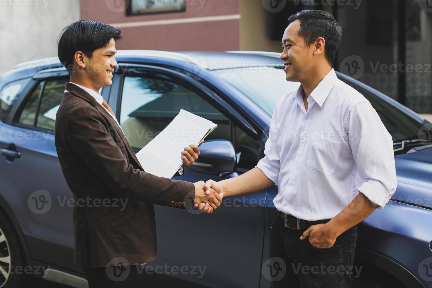 Seller and customer who bought a car shaking hands photo