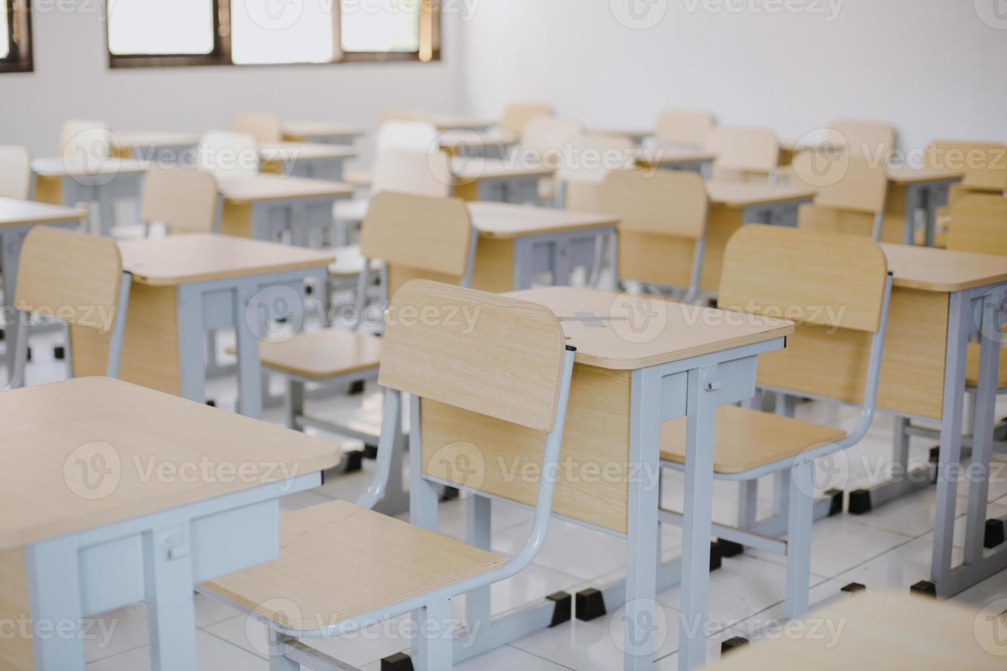 Row of wooden tables and chairs well arranged in empty classroom photo