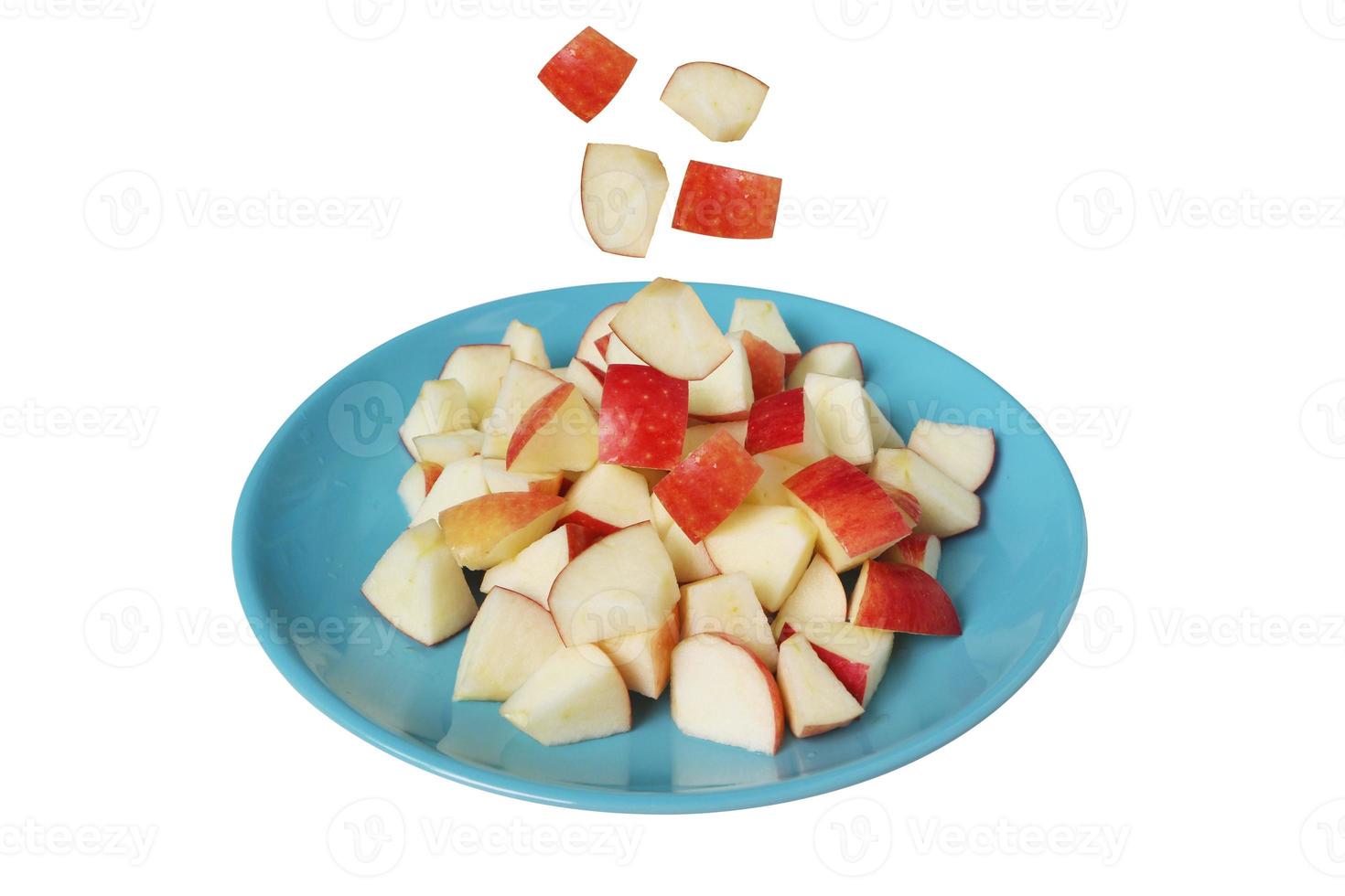 Apple slice falling down to the blue dish isolated on white background with clipping path. photo