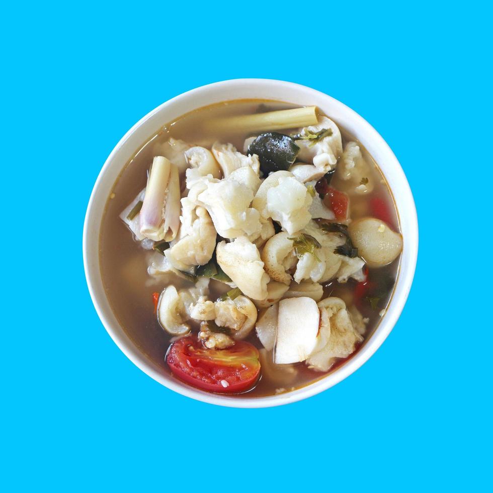 Tom Yum Pork Leg or spicy soup with pork leg in Ceramic Cup isolated on blue background with clipping path. photo