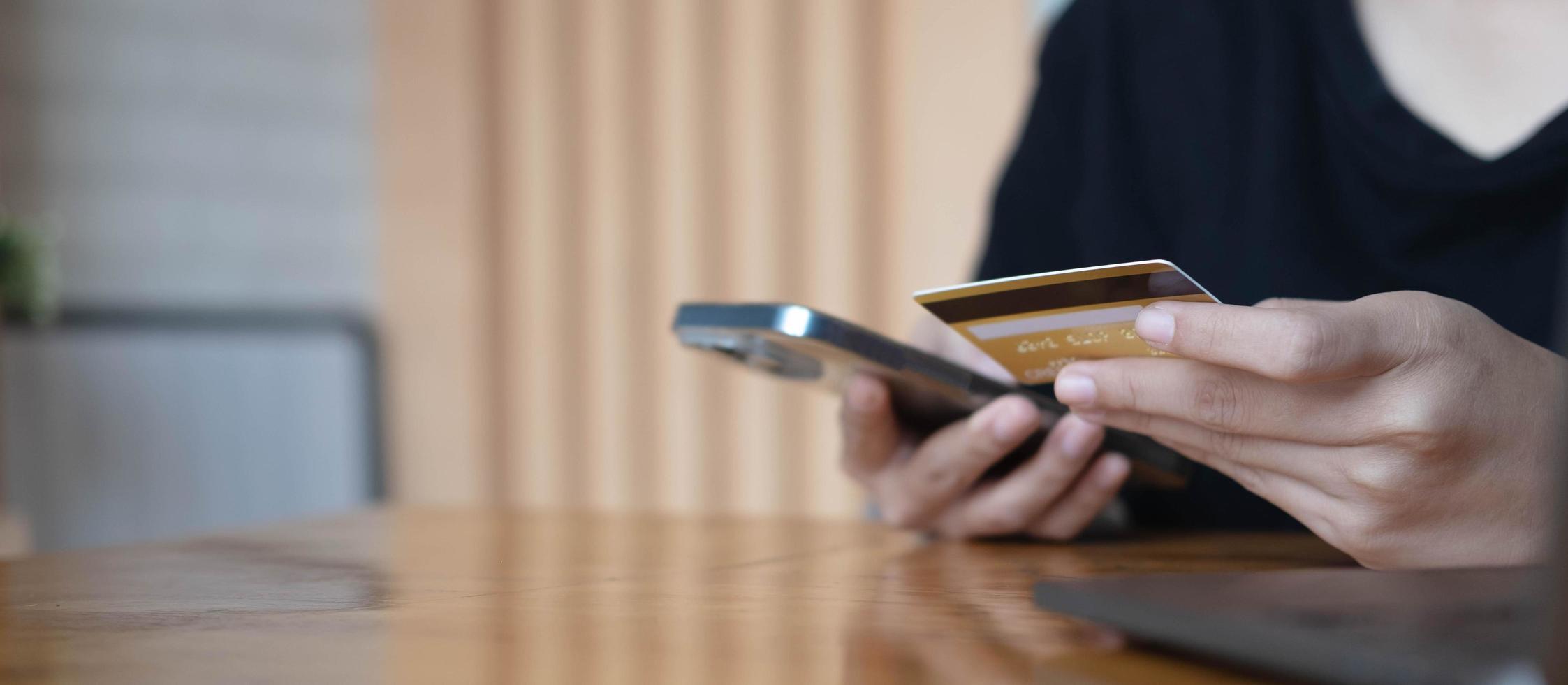 Close up woman hand using credit card and smartphone laptop for buying online shopping photo