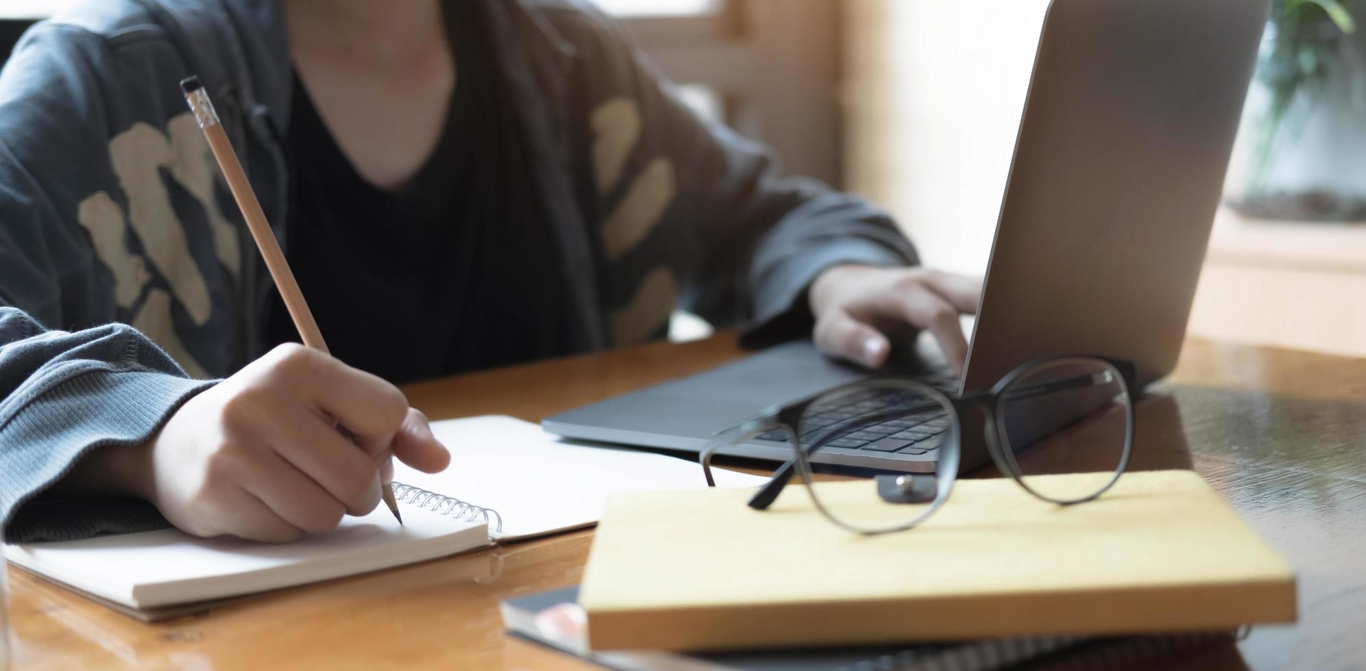 cerrar a las mujeres que usan una computadora portátil y anotar algunos datos en el bloc de notas foto