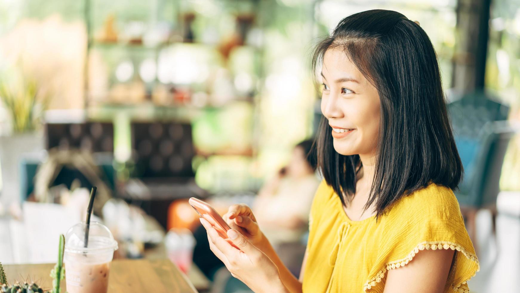Adult happy asian woman using mobile phone at indoor cafe on day. photo