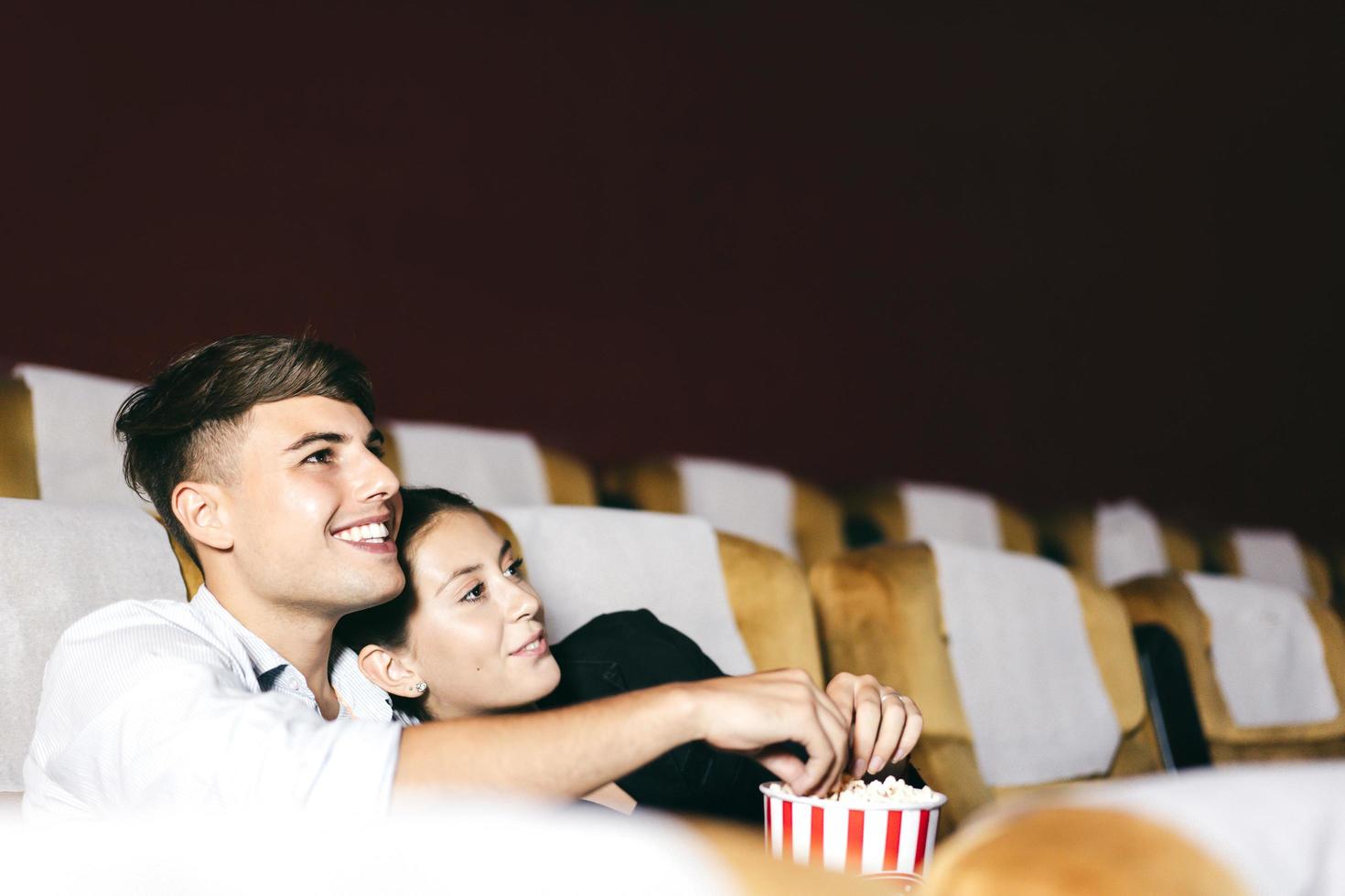 Caucasian man and woman watching movie in theater. photo