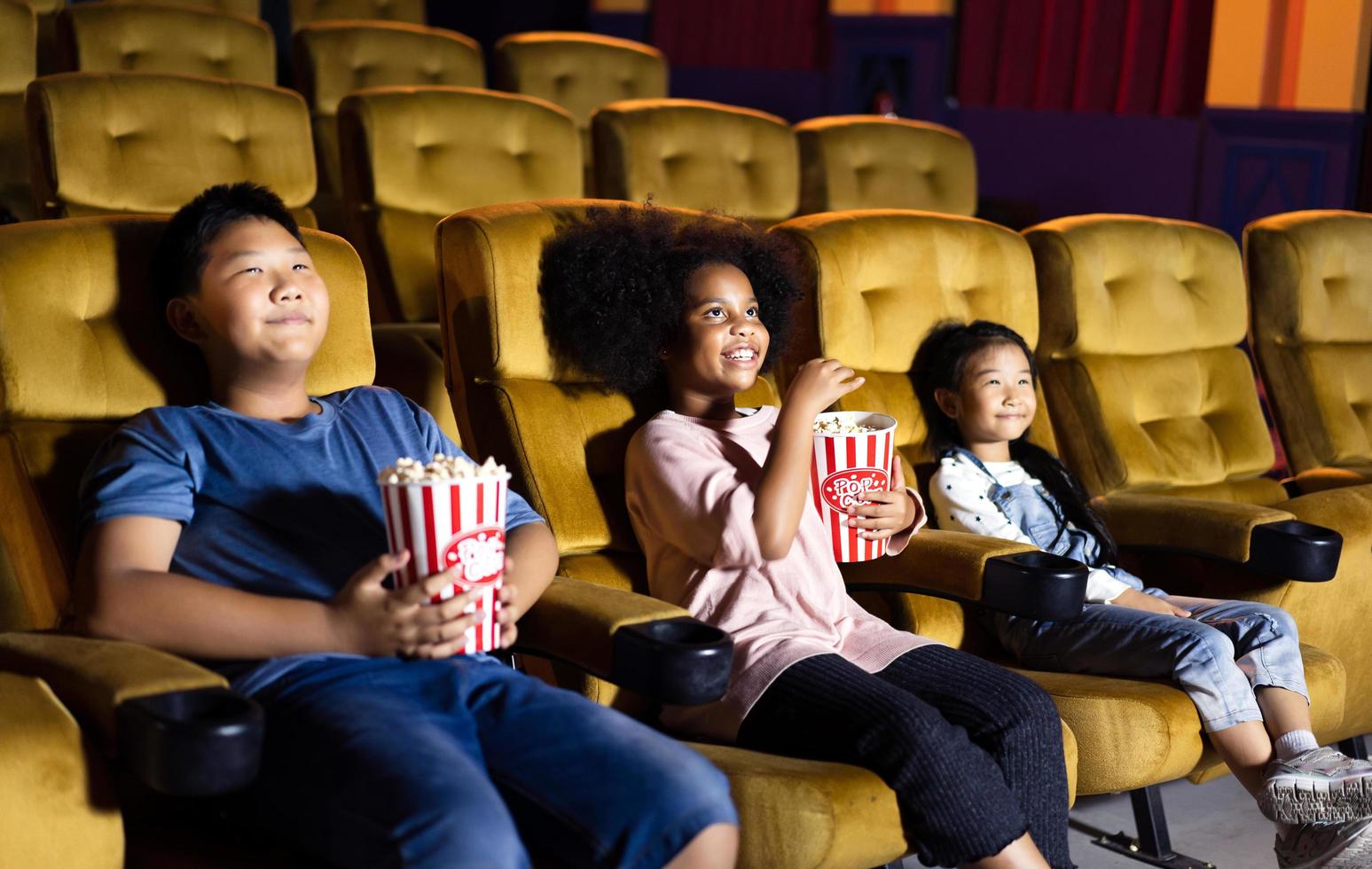 grupo de niños ve una película en el teatro con amigos. foto