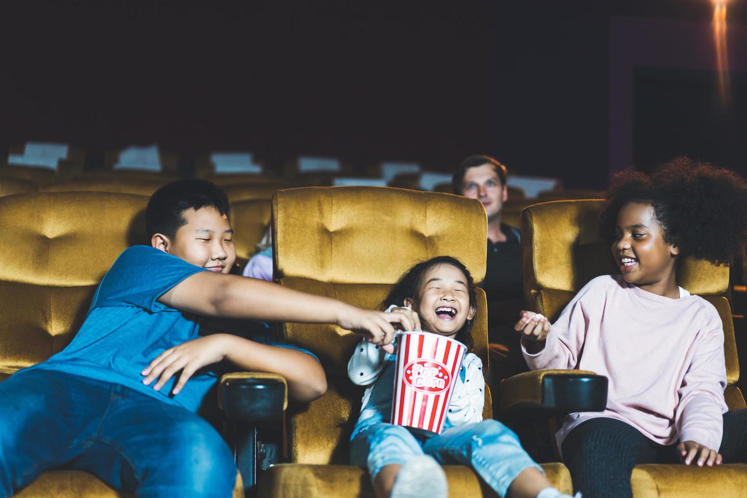niño asiático y niña africana ven una película en el teatro concepto de cine divertido. foto