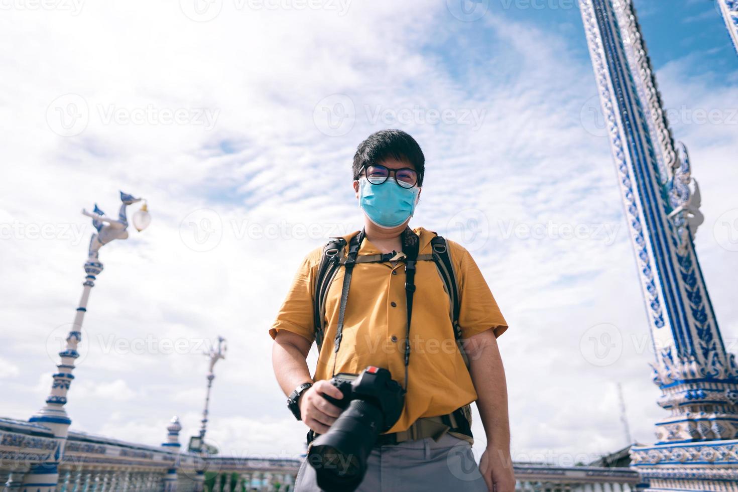 Adult asian traveller photographer man with mask on face for new normal outdoor lifestyle photo