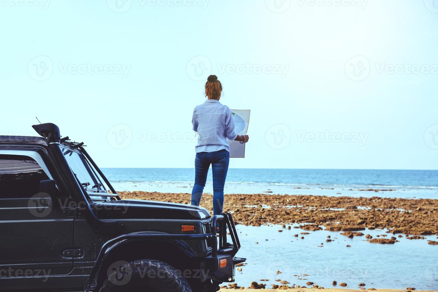 Asian woman travel nature. Travel relax. Stand on the car and In the map handle at the beach.In the summer. Thailand photo