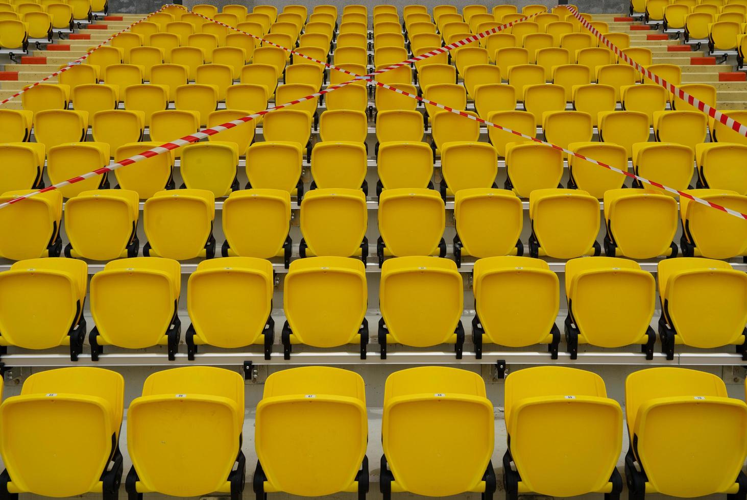 The seats in the football fields were blocked from sitting,Yellow chairs on the football field forbid people to sit. photo