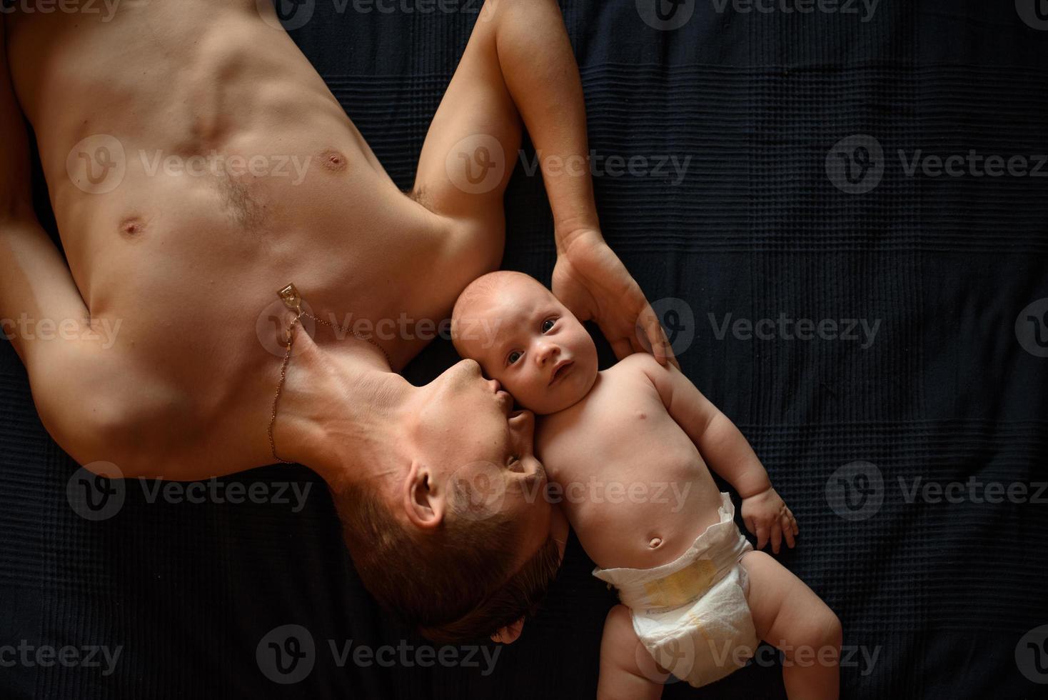 A young father lies next to his little son photo