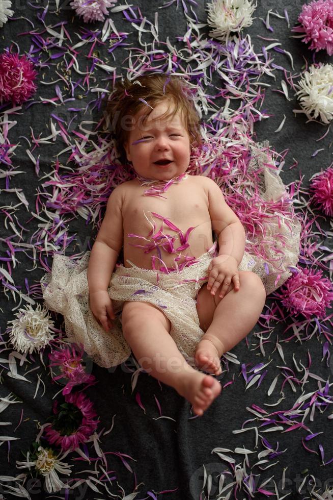 Portrait of a sweet little baby girl with a wreath of flowers on her head indoors photo