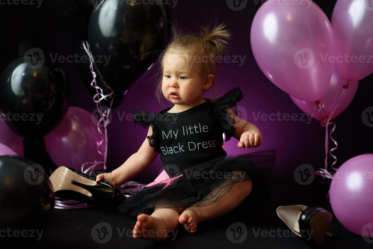 first year baby girl's birthday party day. ballons and holiday indoors. child's birthday. little pretty girl in her first black dress photo
